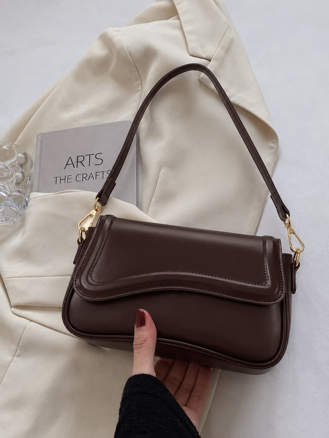Dark brown curved-flap shoulder bag with gold-tone strap clips